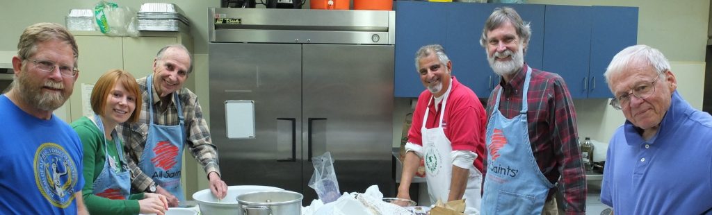 A group of adults smiling while preparing food.